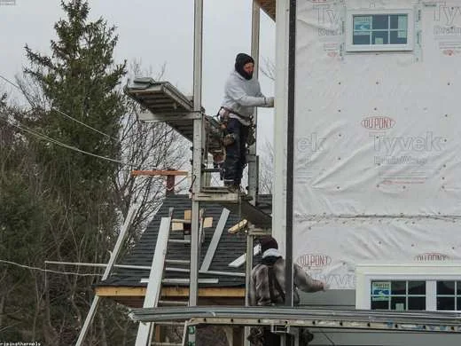 Workers adding insulation and weather protection to a house exterior
